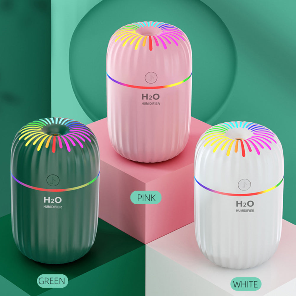 Three colorful humidifiers in pink, green, and white on a geometric background