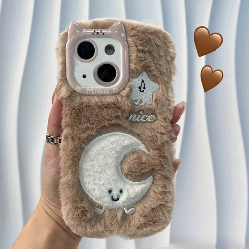 Fluffy phone case with cute designs held by a hand against a light curtain background