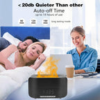 Black device with flame design on a table, people in bed, and a woman working on a laptop in the background. Emiravaly