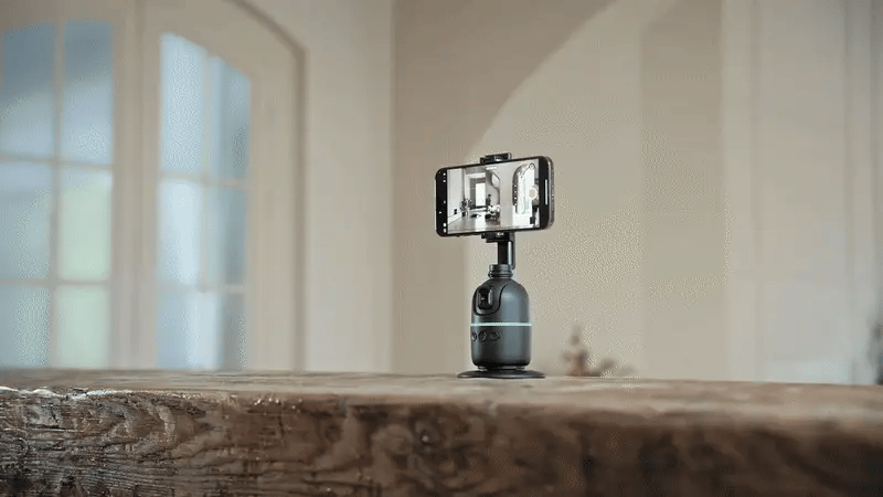 Bottle on a wooden surface with a smartphone and lamp setup for a selfie.