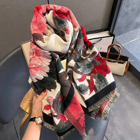 Colorful patterned scarf held by a hand with a watch, against a neutral background.Emiravaly